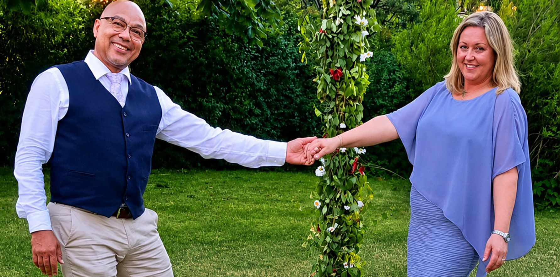 Kristina et Guy se tenant la main dans un décor de fleurs blanches et de feuillage vert